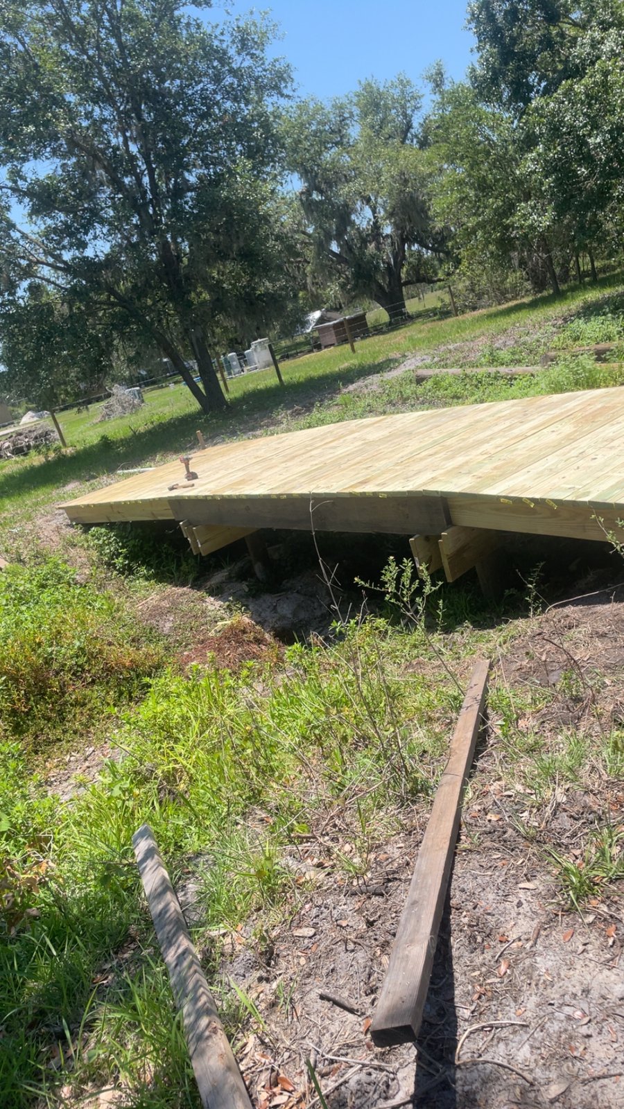 Low wooden deck or garden bridge under construction with drill and hammer on pressure-treated boards