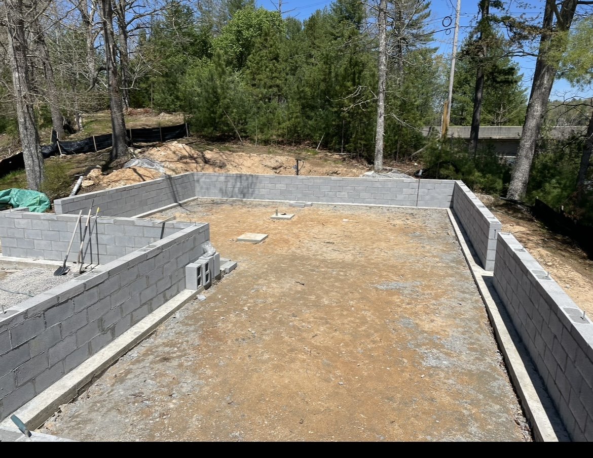 Rectangular concrete block foundation with shovels leaning on the interior wall