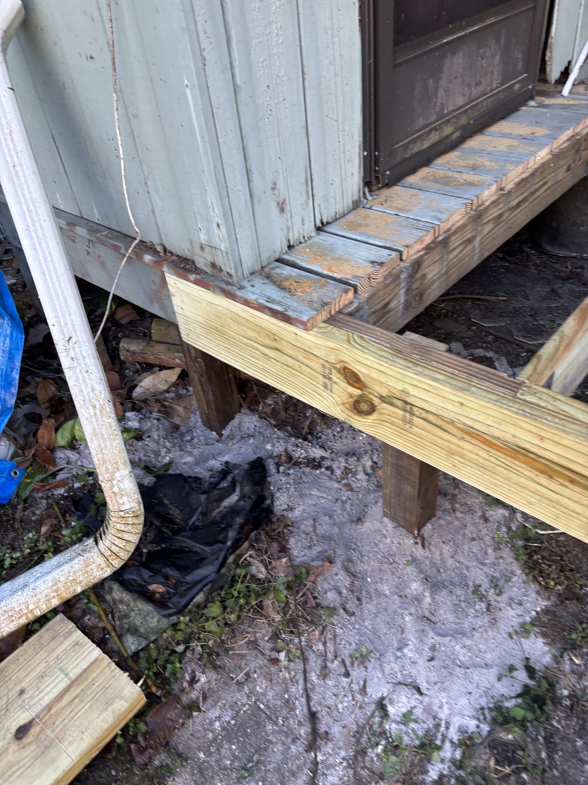 Structural deck repair with new pressure-treated joist and support posts under weathered decking