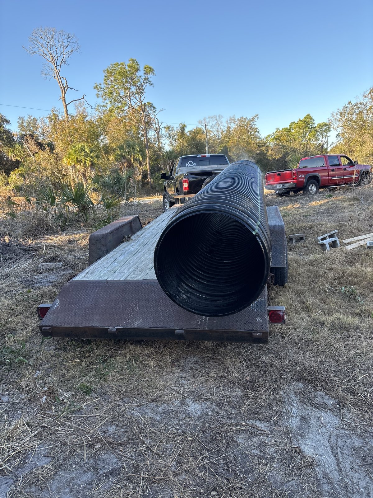 Large black corrugated drainage pipe loaded on a flatbed trailer at a job site