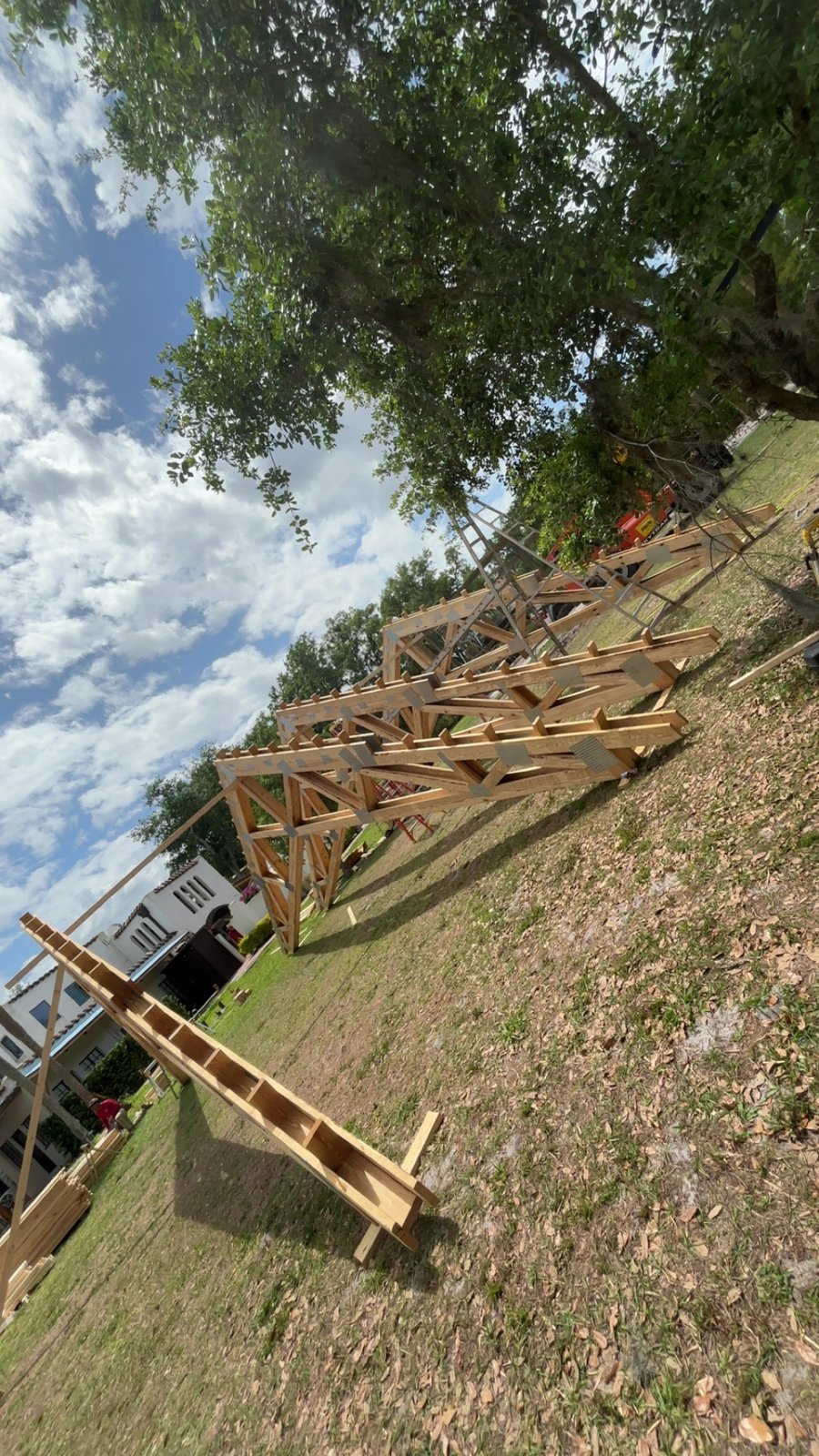 Wooden roof trusses with metal gusset plates staged on a lawn for residential work