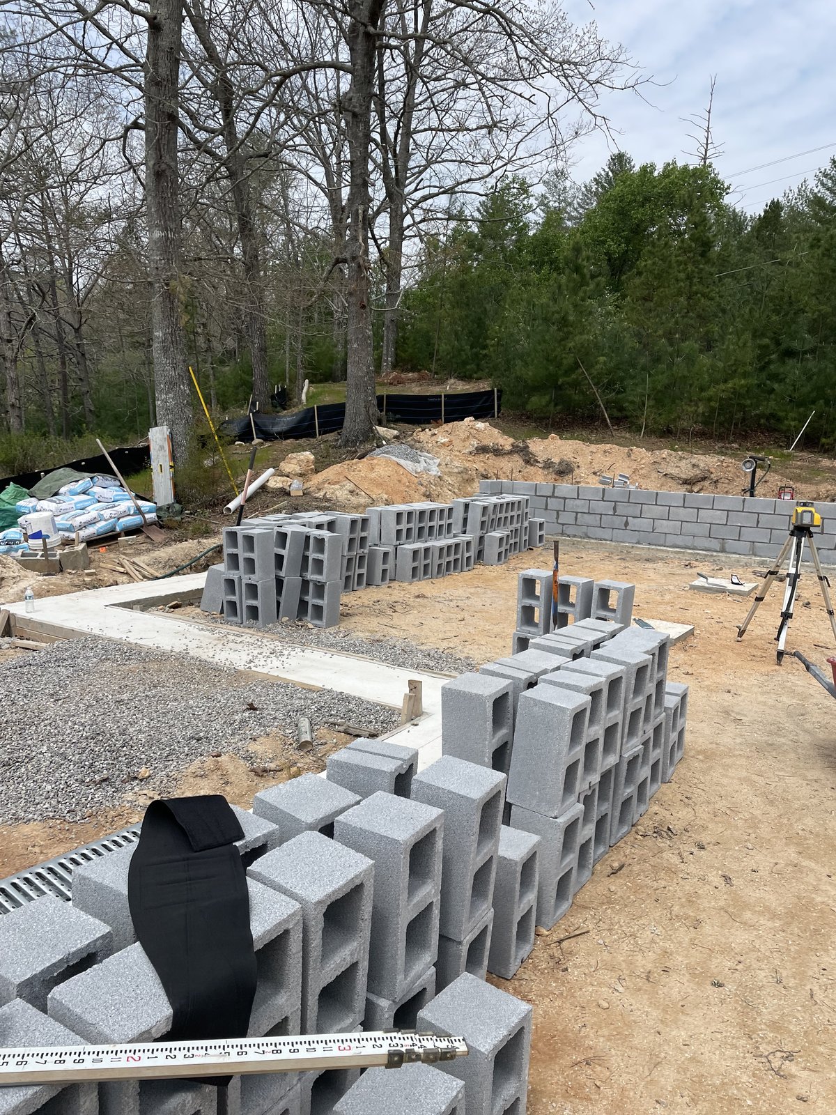 Stacks of concrete blocks and laser level at a foundation masonry site