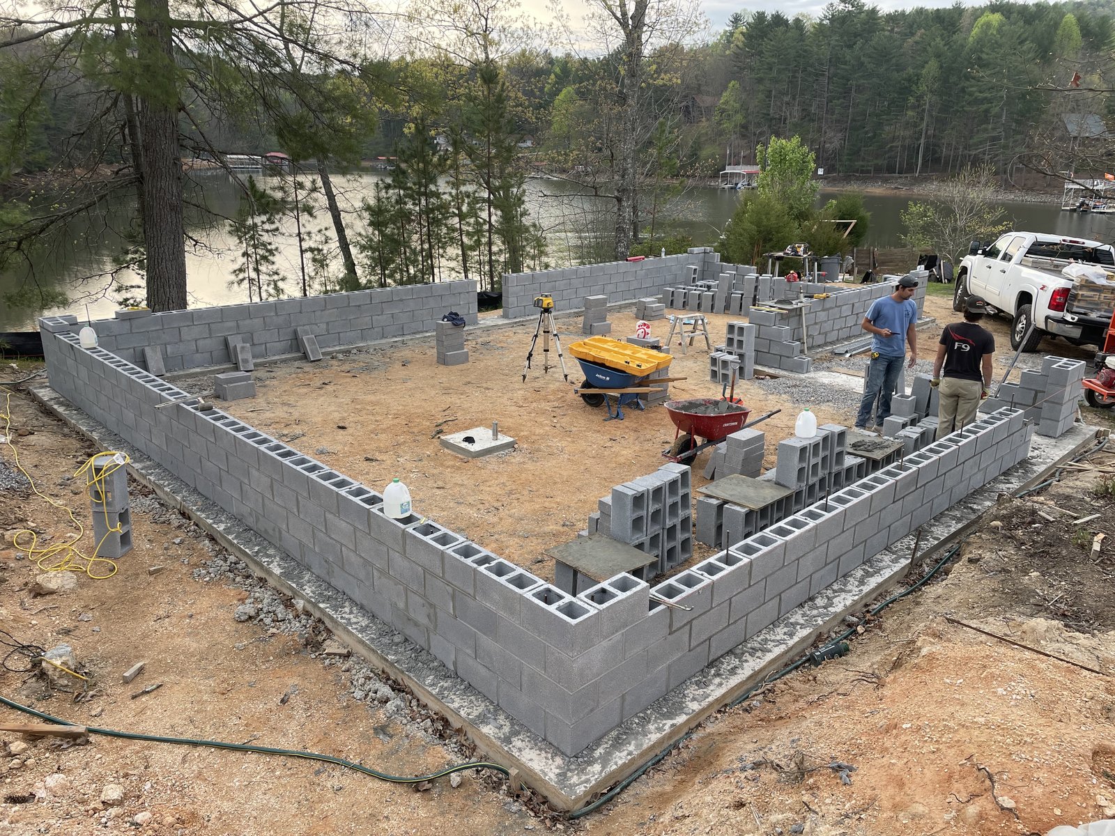 Workers laying concrete block foundation walls on a lakeside lot