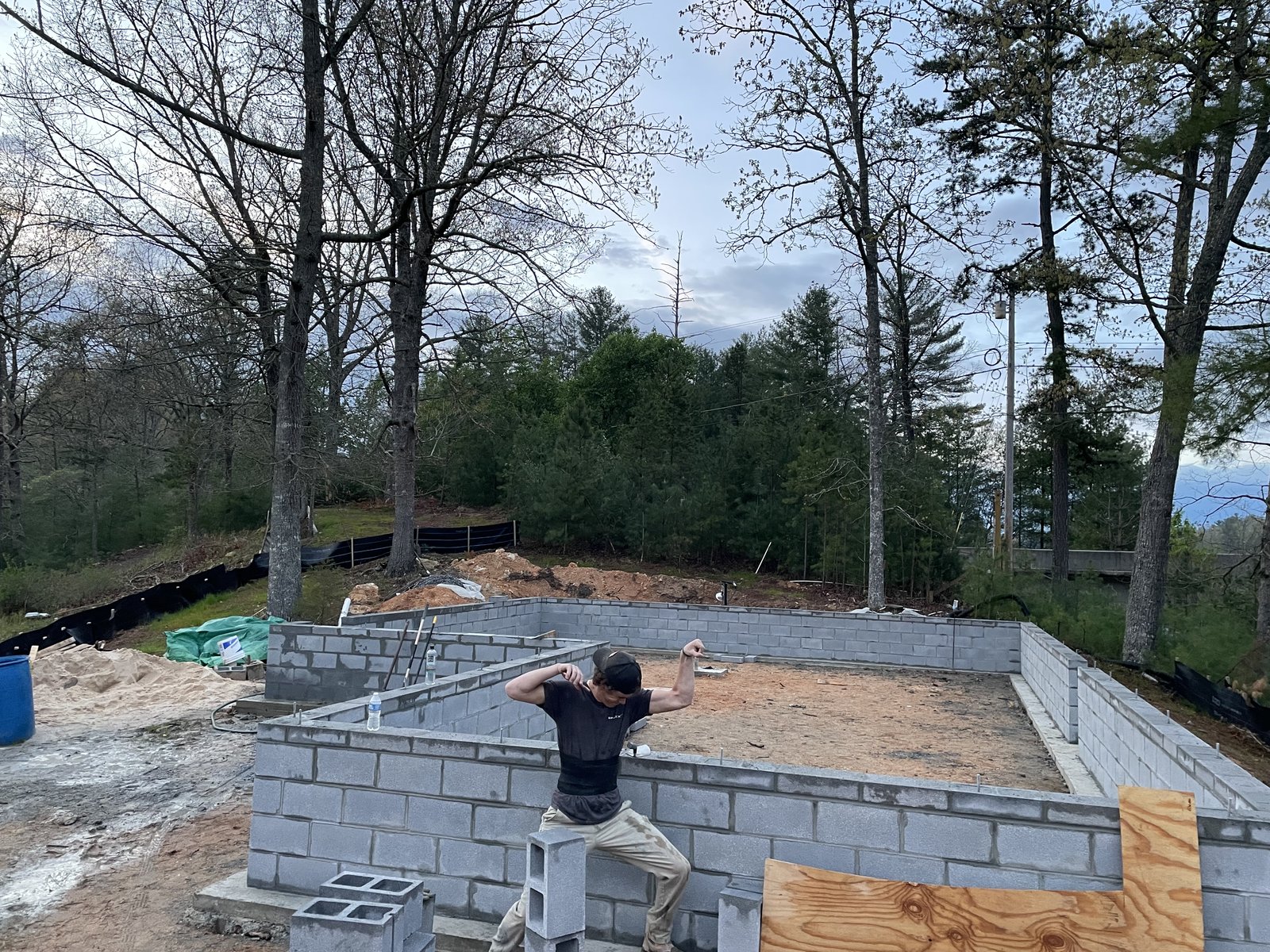 Concrete block foundation walls on a wooded lot with materials stacked on site